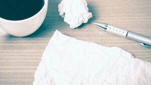 Papier, Stift und Kaffeetasse - Schreibszene. Titelgrafik zum Blogartikel Astrologie und Produktivität